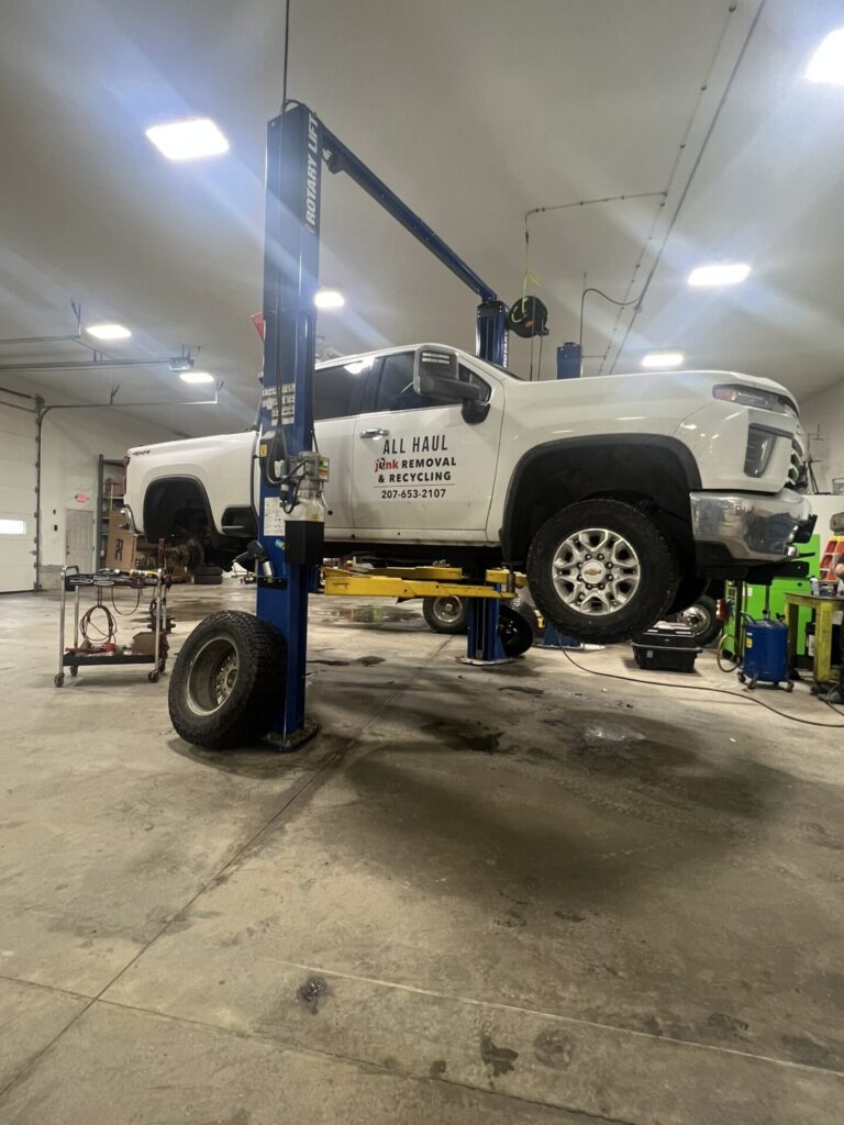 White pickup truck on a lift at Aplus Service Center in Casco, ME